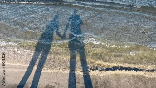 Shadow couple on the beach. Holding hands. Summer time, holidays vibes Soft wave background.