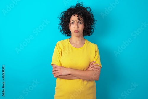 Billede på lærred Gloomy dissatisfied young arab woman wearing yellow T-shirt over blue background