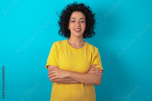 Foto Portrait of charming young arab woman wearing yellow T-shirt over blue backgroun