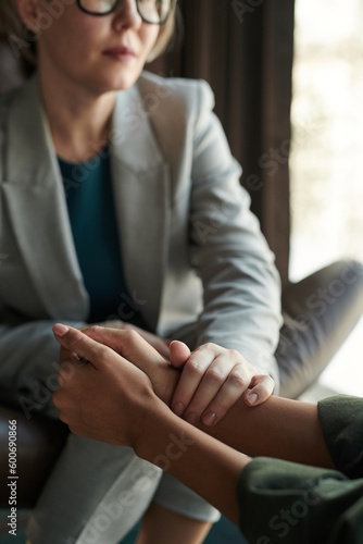 Slika na platnu Close-up of experienced psychologist keeping hand on those of young depressed fe