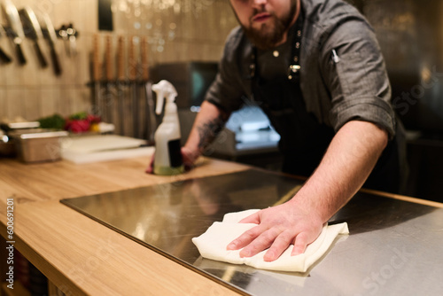 Fotografie Close-up of young professional chef sanitizing and cleaning surface of electric