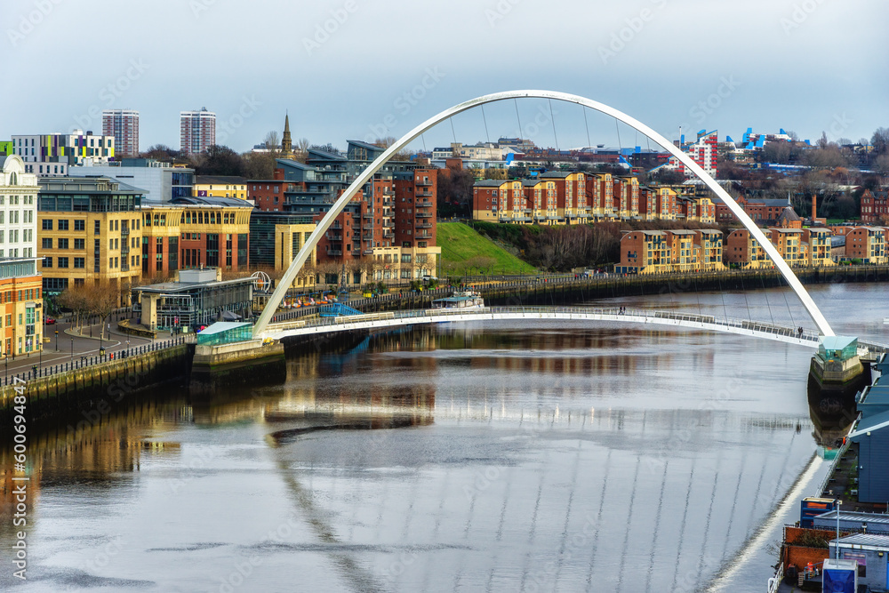Fototapeta premium Gateshead Millennium Bridge crossing River Tyne in Gateshead, with a view of Newcastle upon Tyne, UK