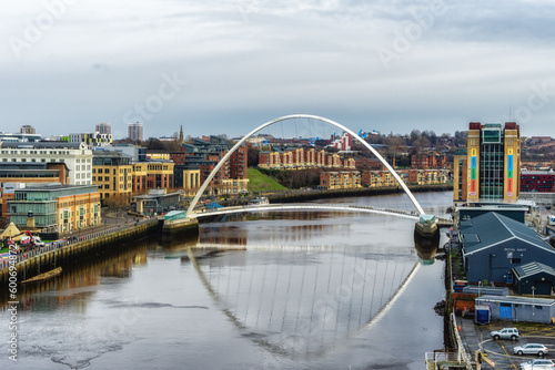 Gateshead Millennium Bridge crossing River Tyne in Gateshead, with a view of Newcastle upon Tyne, UK photo