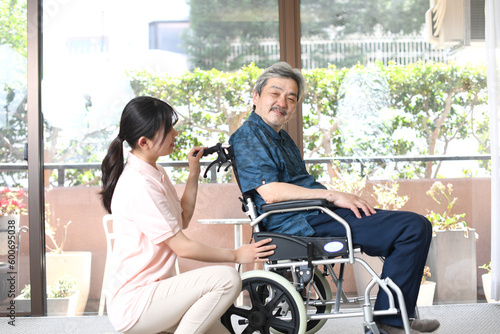 若い介護士の女性と車椅子に乗るシニア男性