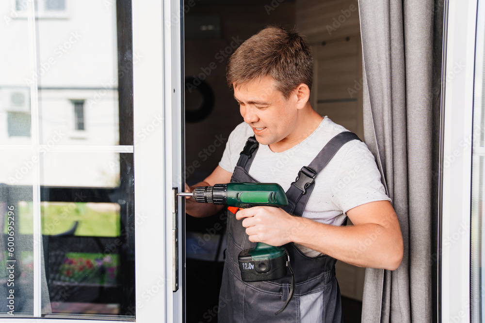 A repairman repairs or adjusts window frames or glass doors on the terrace. A repairman repairs or adjusts window frames or glass doors on the terrace.