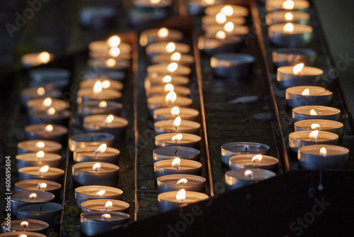 Fototapeta Close-up shot of multiple lit votive candles in a church setting, with a blurred