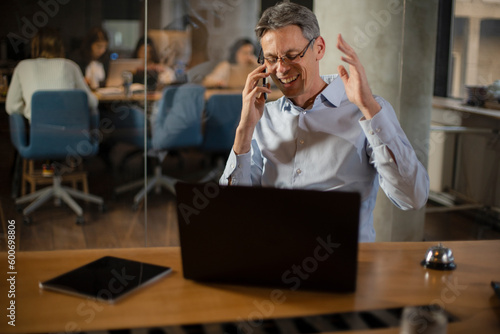 Businessman in office. Handsome man talking on phone at work.