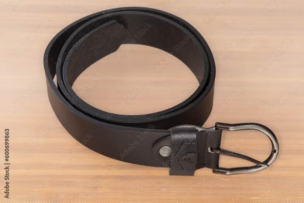 Black leather belt with semicircular frame buckle on light surface Black leather belt with semicircular frame buckle on light surface