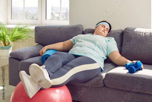 Funny fat woman sleeping on couch instead of having active fitness workout with sports equipment. Lazy plump overweight girl sleeping on sofa with fit ball and dumbbells. Lack of motivation concept