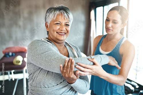 Stretching, support and old woman with personal trainer for fitness, wellness or rehabilitation. Health, workout or retirement with senior patient and female trainer in gym for arm warm up training