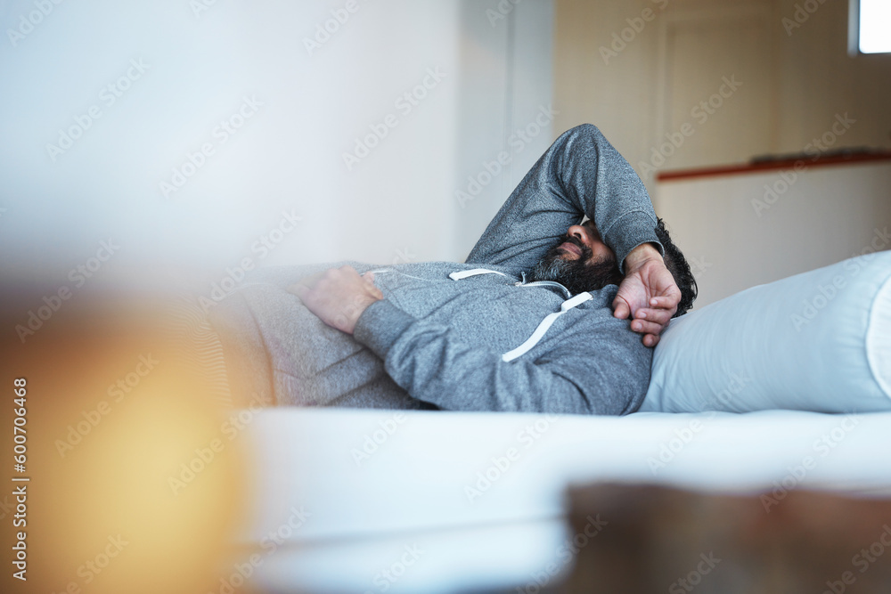 Tired, insomnia and a man with stress on a bed with burnout, sad and mental health problem. Fatigue, depression and a person sleeping in the bedroom of a house while depressed or sick with a hangover