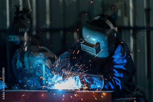 Foto A workers wearing industrial uniforms and welded iron mask at steel welding plants, Industrial safety first concept