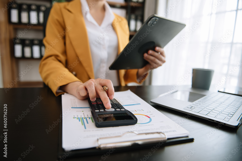 Women counting coins on calculator taking from the piggy bank. hand holding pen working on calculator to calculate on desk about cost at office... Women counting coins on calculator taking from the piggy bank. hand holding pen working on calculator to calculate on desk about cost at office...