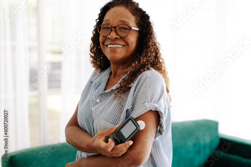 Senior woman using a flash glucose monitor to manage her diabetes at home photo