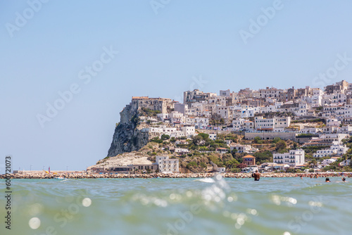 A sea beach with people who rest in the summer on it and buildings of Peschici, Puglia