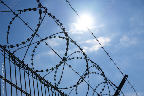 Barbed wire protection fence. Concept photo for security and lack of freedom. Blue sky background.