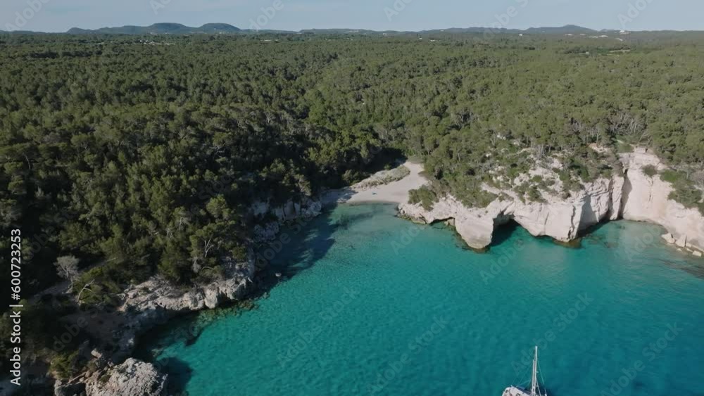 Sailing yacht floating off the coast around Cala Mitjana beach in Menorca displaying a European summer day. Sailing yacht floating off the coast around Cala Mitjana beach in Menorca displaying a European summer day.