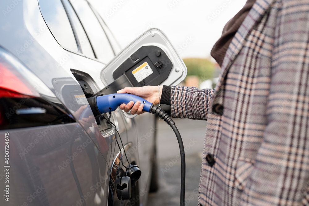 Midsection of woman charging electric car Midsection of woman charging electric car