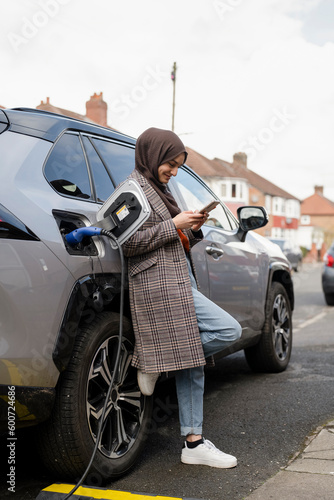 Woman wearing hijab charging electric car