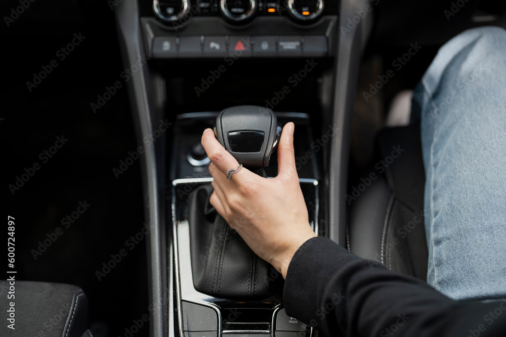Woman holding gear lever in car, close up