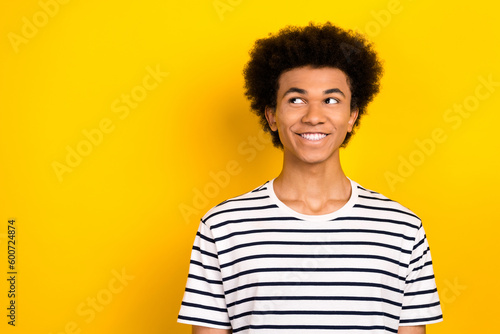 Portrait of handsome young guy wear striped t-shirt smile look empty space toothy beaming happy joyful isolated on yellow color background © deagreez