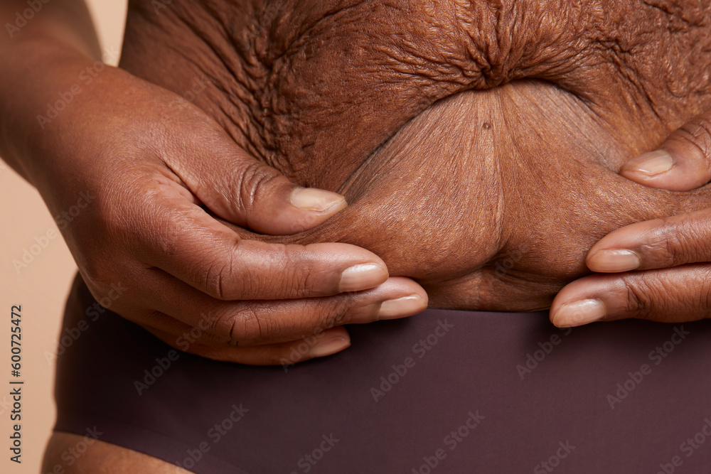 Fototapeta premium Close-up view of senior woman touching wrinkled belly