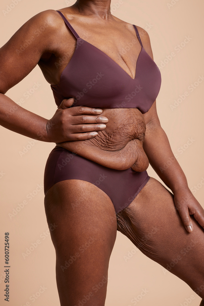 Senior woman standing in underwear against beige background Senior woman standing in underwear against beige background
