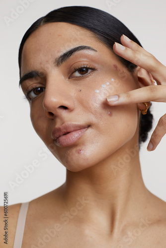 Studio shot of young woman applying cream on face photo