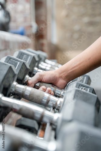 Woman picking dumbbell from gym rack