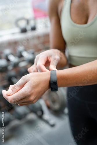 Woman putting fitness tracker on hand at gym