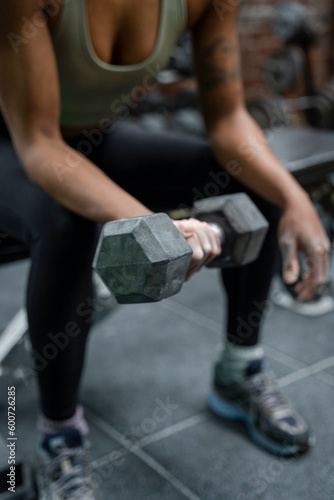 Woman holding dumbbell during weight training on gym