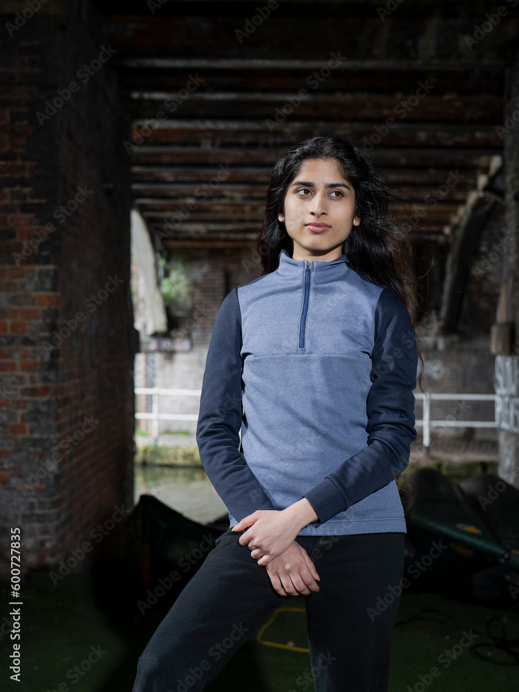 Young brunette woman standing below bridge near canal