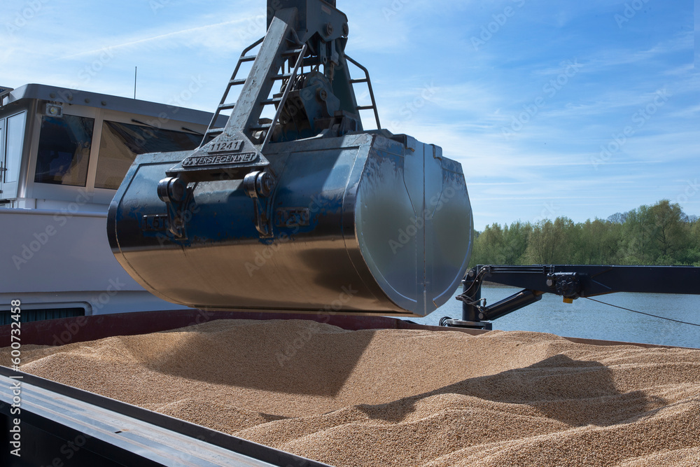 Unloading a ship of soja beans by crane. Barge. Inland vessel. River. Transport by ship. Cattle feed. Cranebox. Unloading a ship of soja beans by crane. Barge. Inland vessel. River. Transport by ship. Cattle feed. Cranebox.