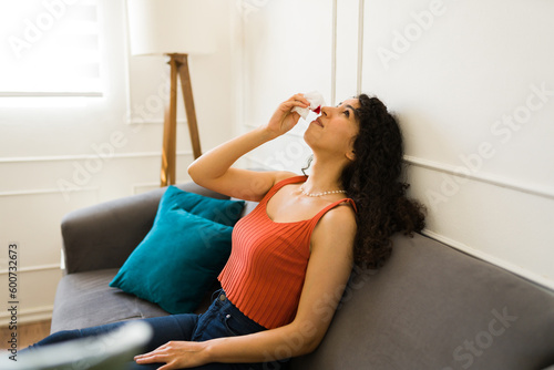 Beautiful latin woman suffering from nosebleed at home photo