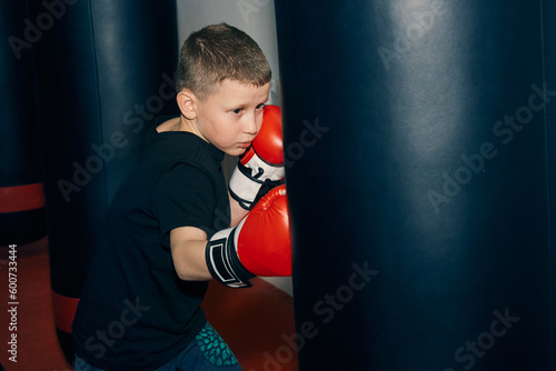 boy in boxing gloves hits a punching bag.