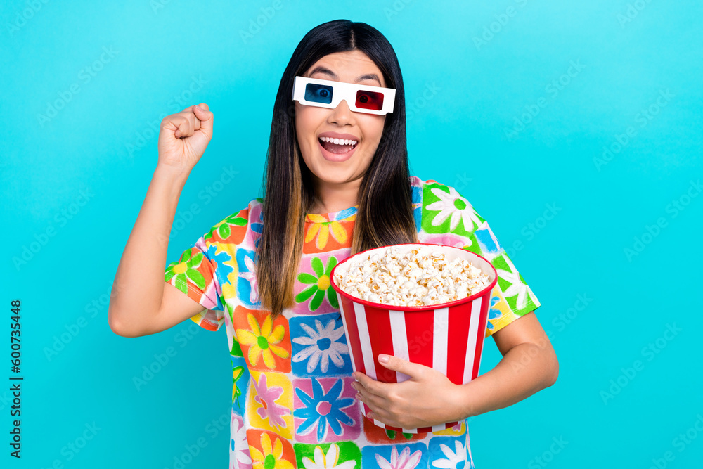 Photo of funky lucky woman dressed flower print t-shirt rising fist eat pop corn watching vr film isolated blue color background