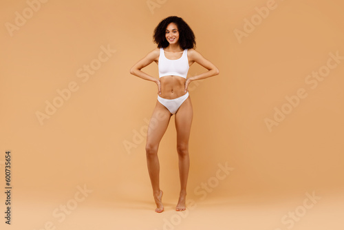 Obraz na plátně Full body length shot of slim black woman posing in white underwear, showing per