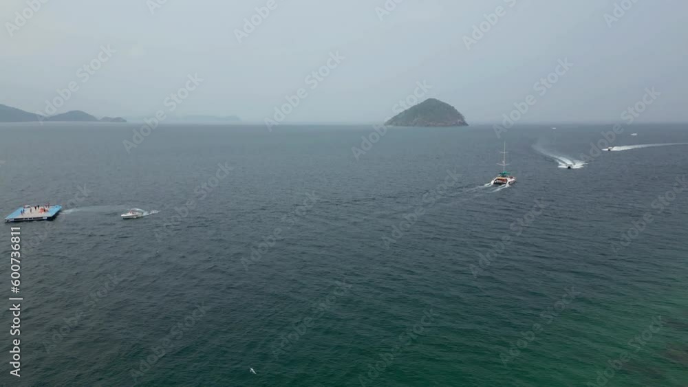 Aerial view from drone of tiny islands on horizon near Phuket, Thailand and Coral Island. Speedboats and catamarans for summer boating fun in a tropical paradise tourist destination. Tilt up reveal Aerial view from drone of tiny islands on horizon near Phuket, Thailand and Coral Island. Speedboats and catamarans for summer boating fun in a tropical paradise tourist destination. Tilt up reveal