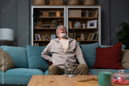 фотографія Aged grey haired senior red face man writhes in pain suffers from low back strain, touch rubbing or massaging loin reduces backache