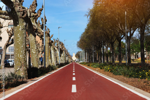 New red bikepath or pedestrian path separated by white line, traffic signs in the park. Bicycle path in European city, Spain. Two way cycle lane on an avenue. Urban traffic and transportation photo