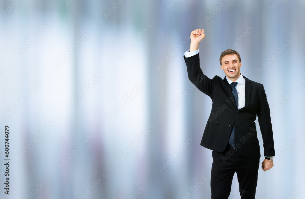 Image of very happy, excited gesturing business man in black confident formal suit, necktie, raising hand fist, on blurred office background. Advertisement ad concept photo Image of very happy, excited gesturing business man in black confident formal suit, necktie, raising hand fist, on blurred office background. Advertisement ad concept photo