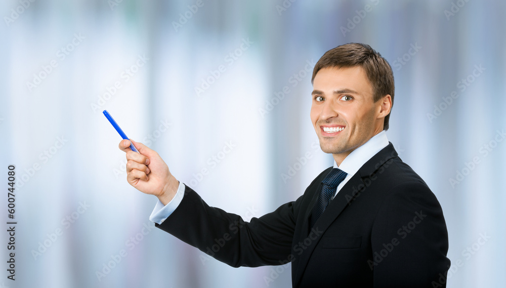 Image of business man in black confident suit, necktie, show pointing advertising product, on blurred office background. Copy space, slogan text area. Image of business man in black confident suit, necktie, show pointing advertising product, on blurred office background. Copy space, slogan text area.