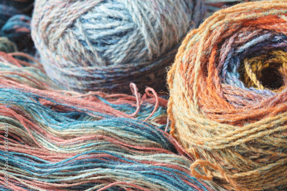 Yarn from natural organic sheep wool. Two balls of multi-colored woolen threads and an unwound skein of rainbow yarn. Yarn from natural organic sheep wool. Two balls of multi-colored woolen threads and an unwound skein of rainbow yarn.