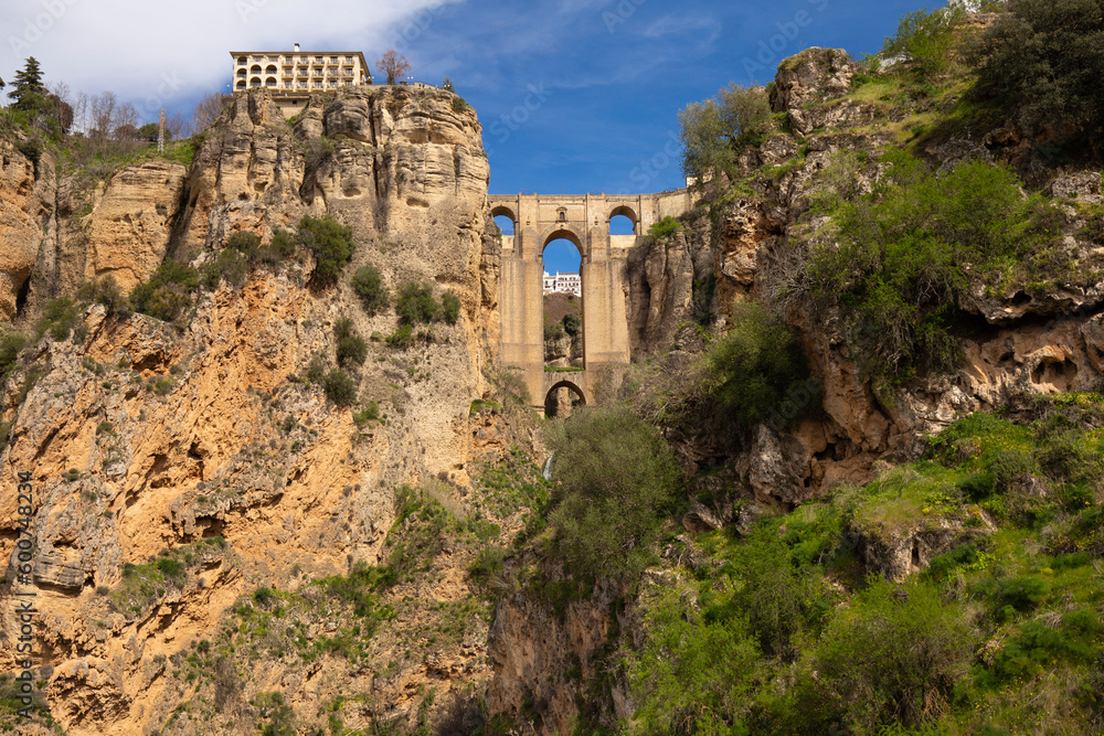 The famous bridge with arched vaults between the rocks of the gorge on a sunny day. Landmark of the city of Ronda, Andalusia, Spain