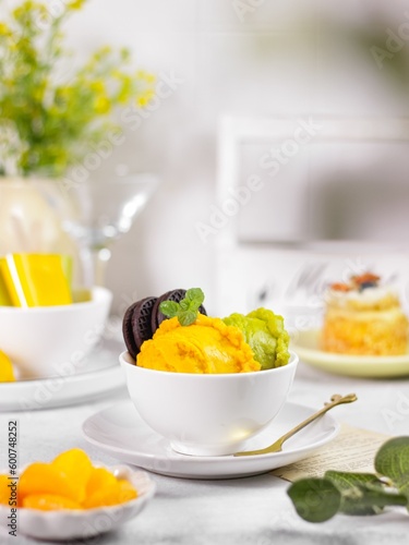 A bowl of ice cream with mango and avocado flavour on the table