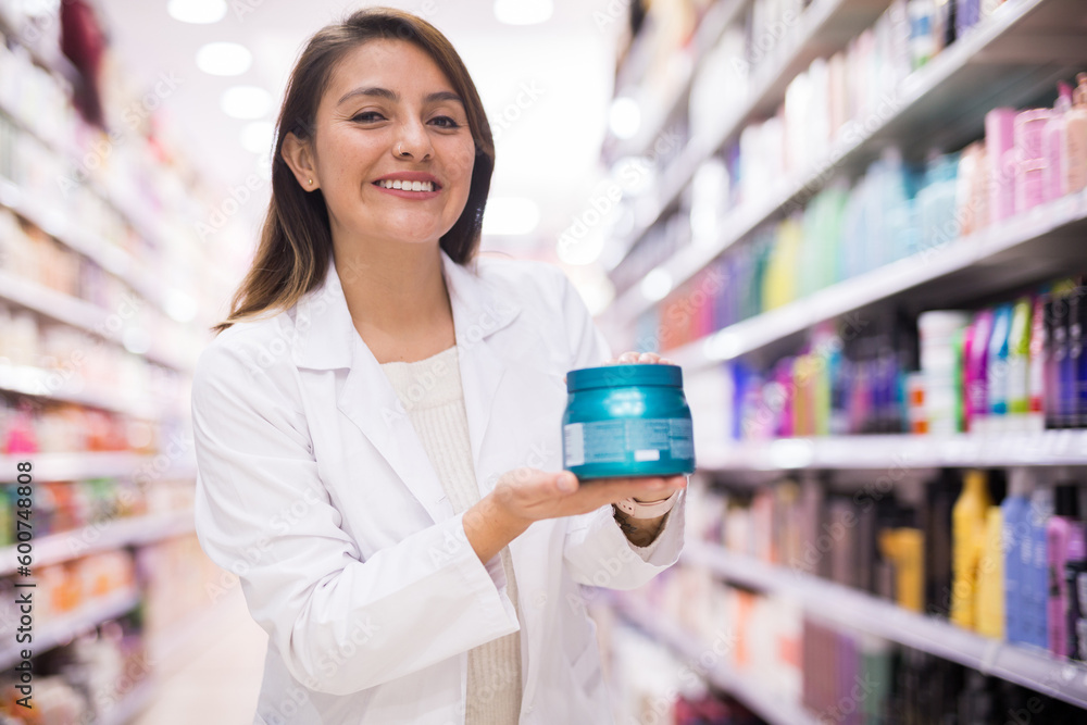 Cheerful saleswoman offering hair care products in cosmetic shop Cheerful saleswoman offering hair care products in cosmetic shop