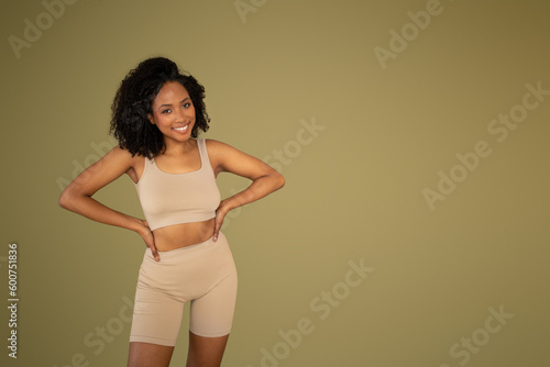 Glad millennial curly african american lady in sportswear look at camera, enjoy sport