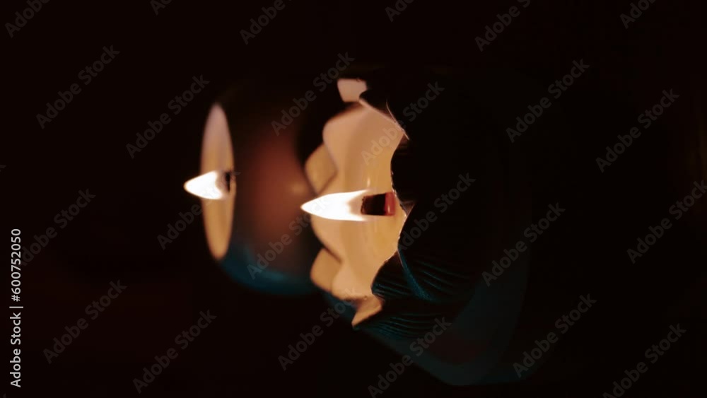 A set of lit white candles flickering in the dark on a black background with one candle in focus in the foreground. Lighting a candle. A burning candle. Beautiful handmade candles. Cozy atmosphere in A set of lit white candles flickering in the dark on a black background with one candle in focus in the foreground. Lighting a candle. A burning candle. Beautiful handmade candles. Cozy atmosphere in