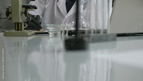 Slow motion, a man in a white coat and glasses carefully writes down the results of the study of a scalapendra in a test tube. Scientific research and teaching activities photo