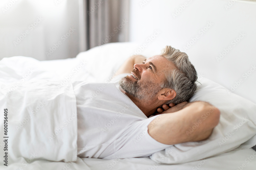 Side view of happy adult man smiling in bed Side view of happy adult man smiling in bed